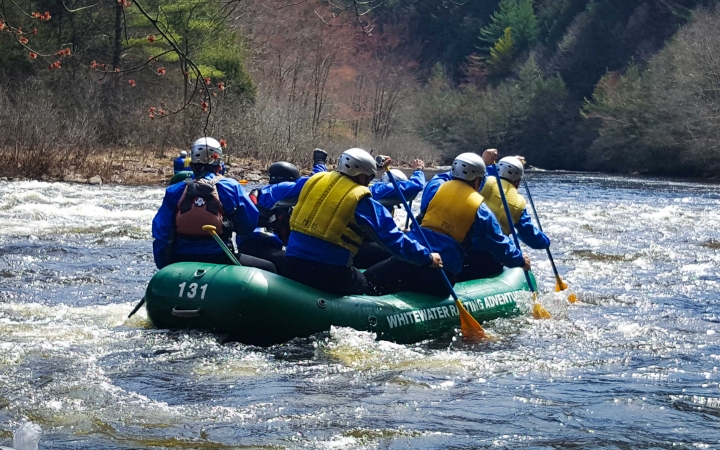 a group of people paddle a raft on an outward bound veterans trip